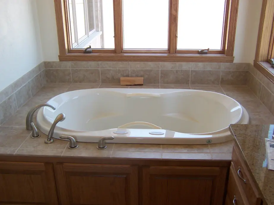 Completed jetted soaking tub with tile surround and oak trimmed window, installed by Keith Petersen Plumbing