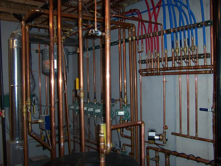 Copper hydronic manifold with red and blue PEX supply lines, valves and circulators, installed by Keith Petersen Plumbing