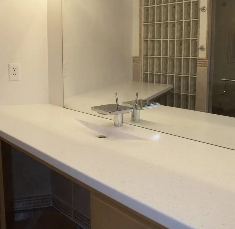 Designer square vessel faucet with a glass block shower behind it