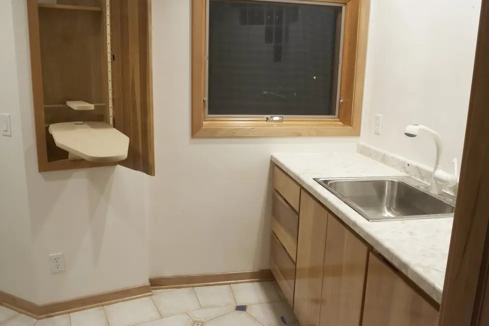 Laundry room utility sink installed beside a built in ironing board cabinet
