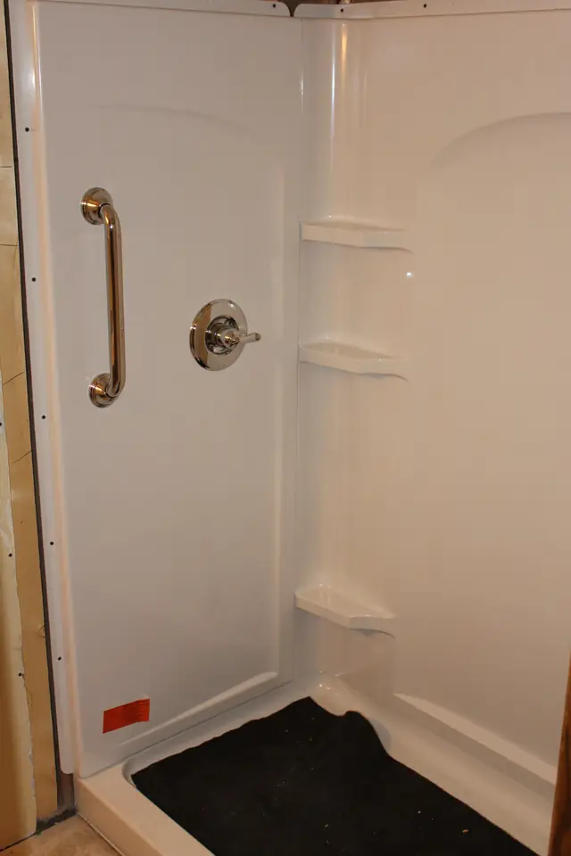 New one piece fiberglass shower stall with a grab bar, still under construction