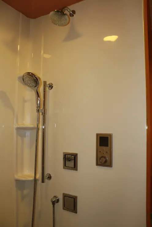 Digital shower control panel installed with a rain head and handheld