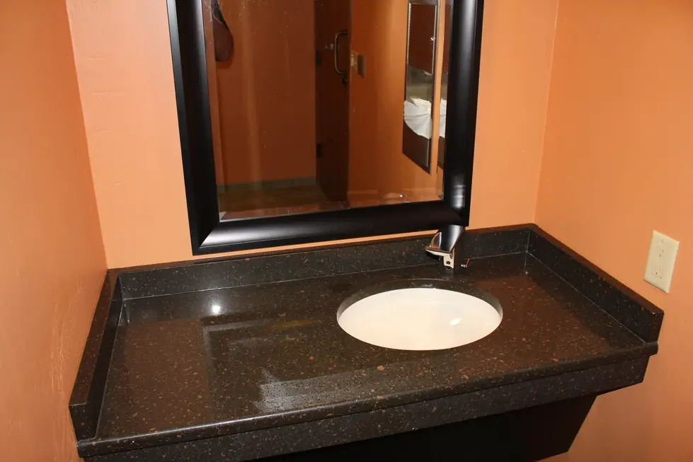Commercial washroom sink on a dark granite counter