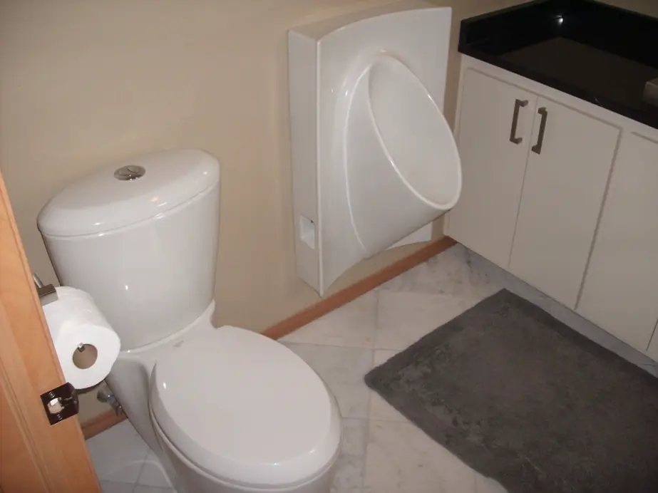 Residential bathroom with a toilet and a wall mounted waterless urinal