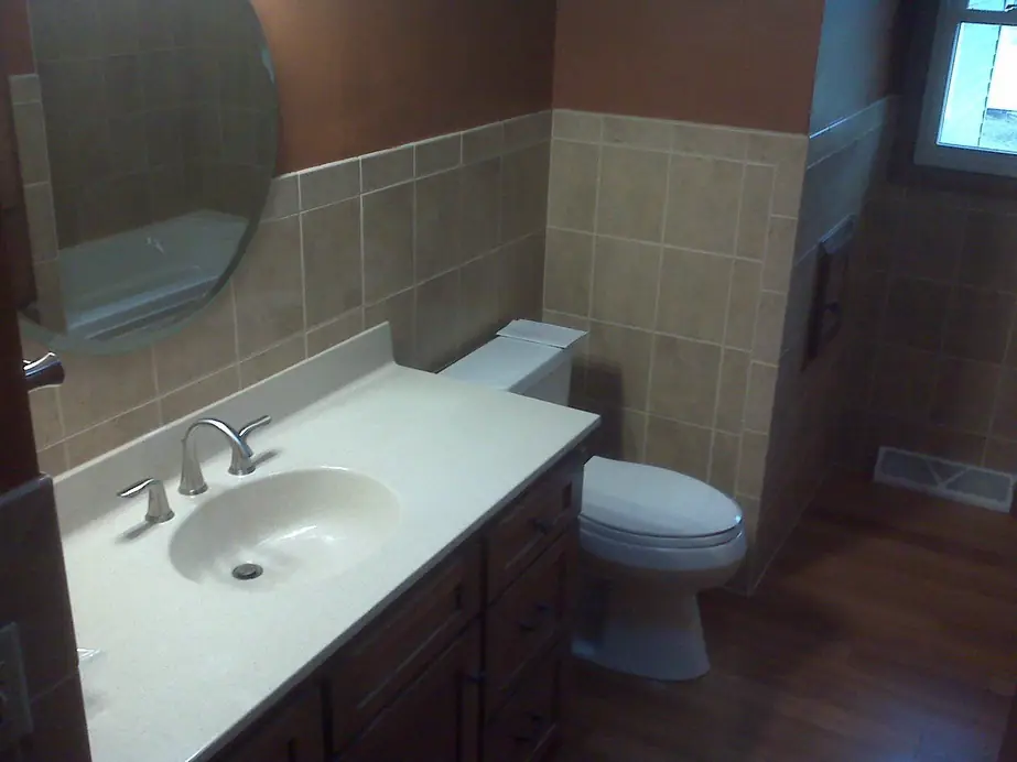 Completed bathroom remodel with vanity, toilet and tile wainscot by Keith Petersen Plumbing