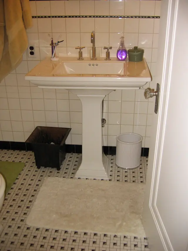 Classic pedestal sink on a black and white basketweave tile floor